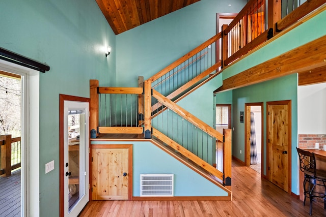 stairs featuring high vaulted ceiling, wood ceiling, and hardwood / wood-style flooring