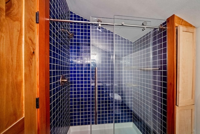 bathroom with tiled shower and a textured ceiling