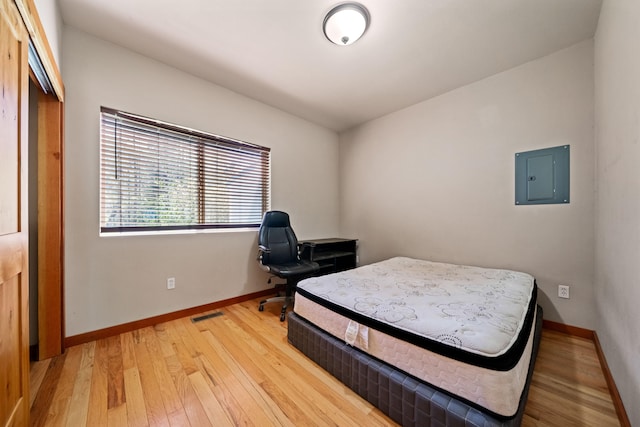 bedroom with electric panel, a closet, and hardwood / wood-style floors