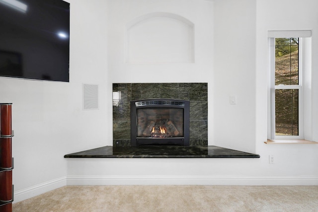 interior details featuring carpet flooring and a tiled fireplace