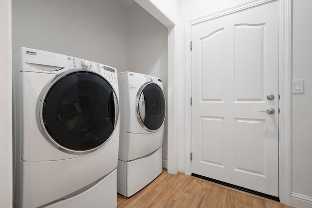 laundry area featuring washer and clothes dryer and light hardwood / wood-style flooring