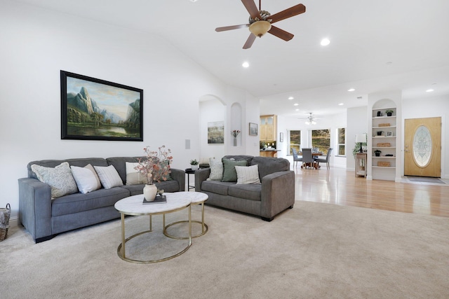 carpeted living room featuring ceiling fan, built in shelves, and lofted ceiling