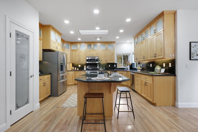 kitchen with a skylight, appliances with stainless steel finishes, light hardwood / wood-style floors, and a kitchen island