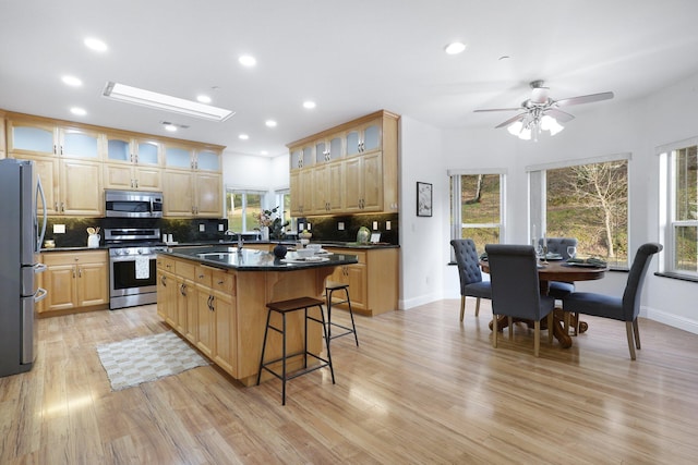 kitchen with ceiling fan, stainless steel appliances, light hardwood / wood-style floors, and a kitchen island