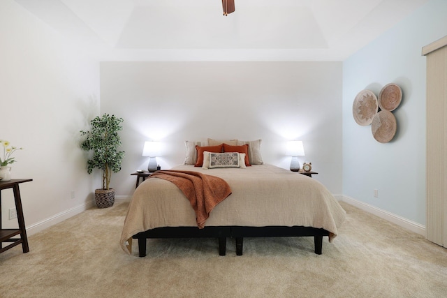 carpeted bedroom with ceiling fan and a tray ceiling