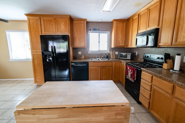 kitchen featuring black appliances, light tile patterned flooring, a kitchen island, and sink