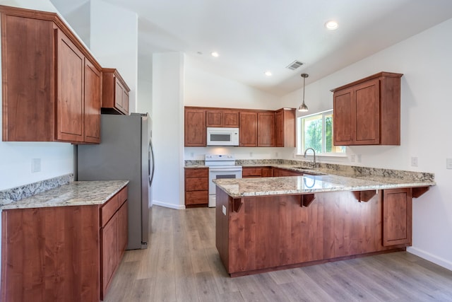 kitchen with kitchen peninsula, vaulted ceiling, decorative light fixtures, white appliances, and light wood-type flooring