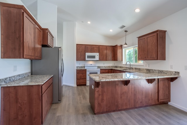 kitchen with kitchen peninsula, light hardwood / wood-style floors, vaulted ceiling, decorative light fixtures, and white appliances