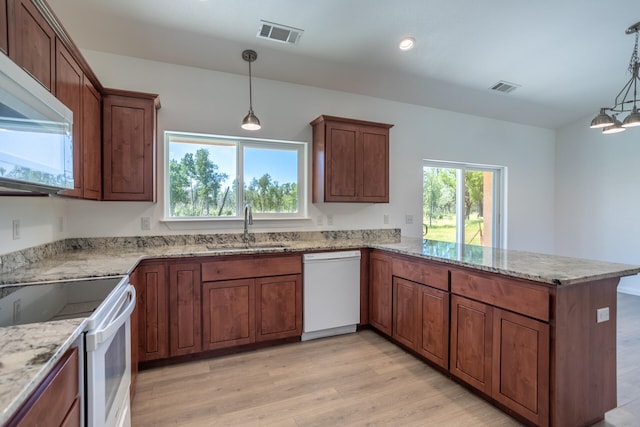 kitchen featuring pendant lighting, white appliances, sink, and light hardwood / wood-style flooring