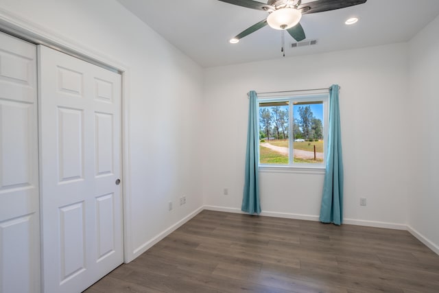 unfurnished bedroom with ceiling fan, dark wood-type flooring, and a closet