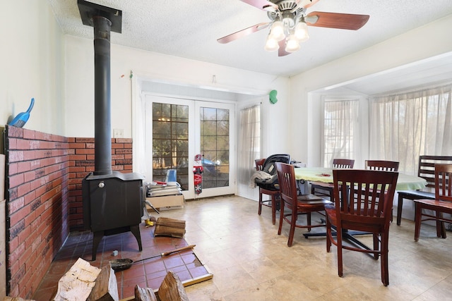 dining area with a wood stove, plenty of natural light, and ceiling fan