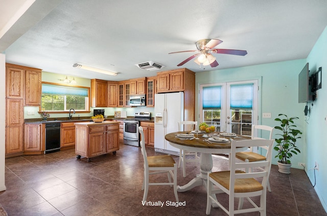 kitchen with ceiling fan, sink, french doors, a kitchen island, and appliances with stainless steel finishes