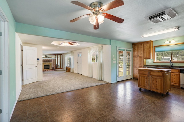 kitchen featuring french doors, dark carpet, a brick fireplace, ceiling fan, and dishwasher