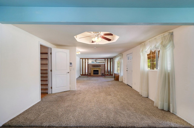 unfurnished living room with carpet, ceiling fan, and a fireplace