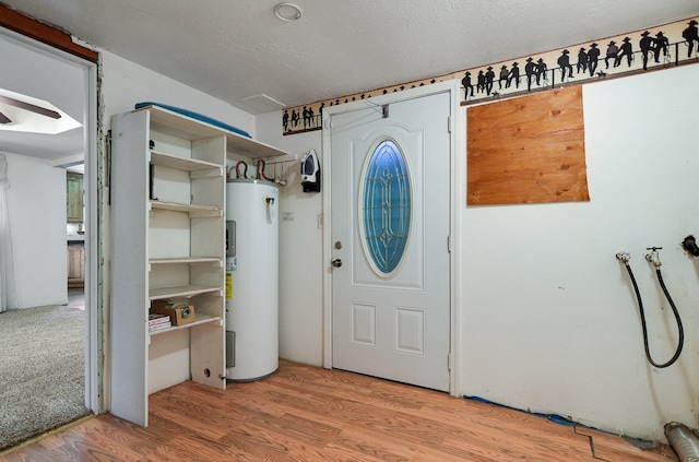 foyer featuring hardwood / wood-style flooring, electric water heater, and a textured ceiling