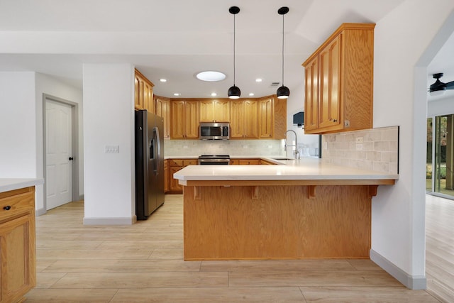 kitchen featuring kitchen peninsula, sink, stainless steel appliances, and light hardwood / wood-style flooring