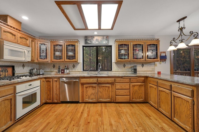 kitchen with sink, stainless steel appliances, light hardwood / wood-style flooring, pendant lighting, and decorative backsplash