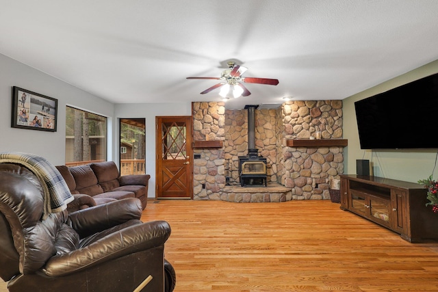 living room with ceiling fan, light wood-type flooring, and a wood stove