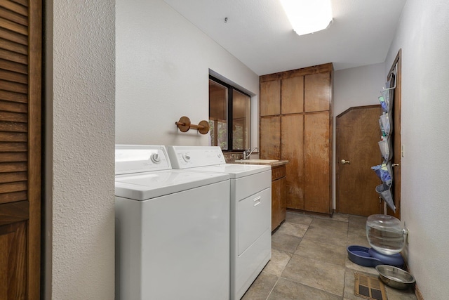 laundry room featuring washer and dryer, sink, light tile patterned floors, and cabinets