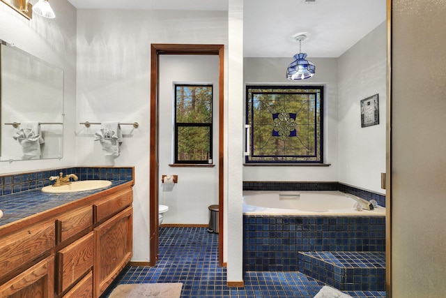 bathroom with tile patterned floors, vanity, toilet, and tiled bath