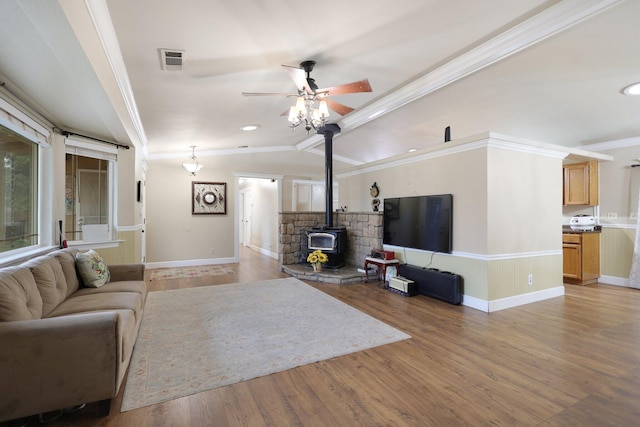 living room featuring a wood stove, crown molding, hardwood / wood-style floors, and lofted ceiling