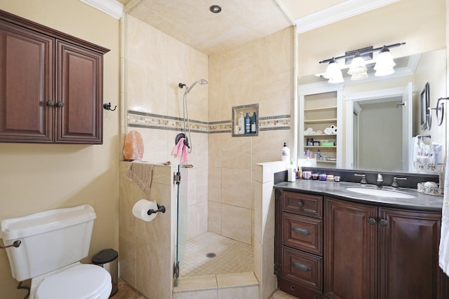 bathroom featuring a tile shower, vanity, toilet, and crown molding