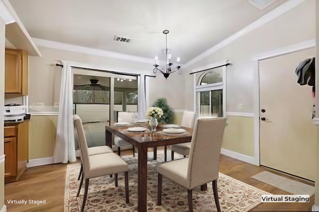 dining space featuring light hardwood / wood-style flooring, a chandelier, and lofted ceiling