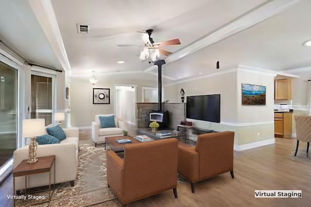 living room with lofted ceiling, ceiling fan, light wood-type flooring, and a wood stove