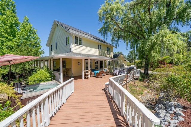 back of house featuring a deck and a hot tub