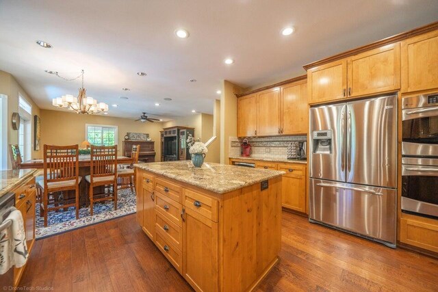 kitchen featuring light stone counters, a kitchen island, dark wood-type flooring, and appliances with stainless steel finishes