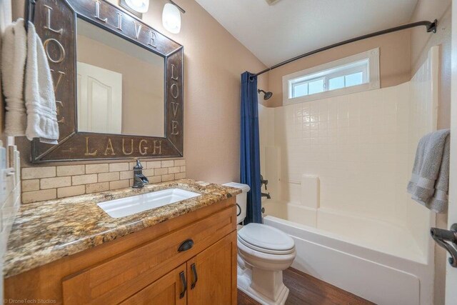 full bathroom with vanity, shower / washtub combination, hardwood / wood-style flooring, toilet, and tasteful backsplash