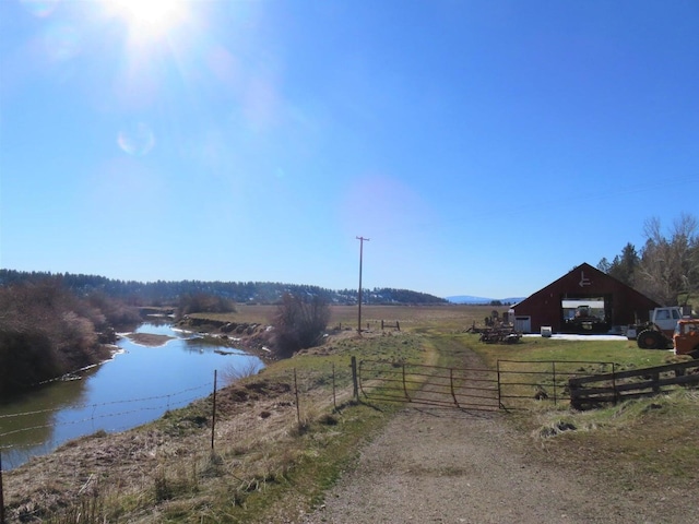 exterior space featuring a rural view, a water view, and an outbuilding