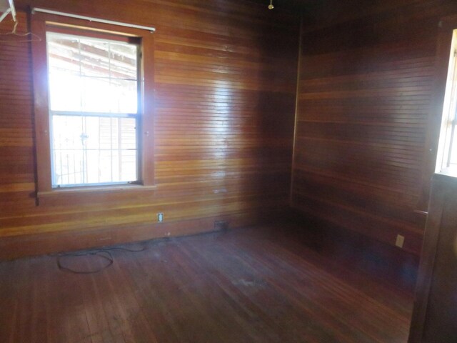 empty room with hardwood / wood-style flooring and wooden walls