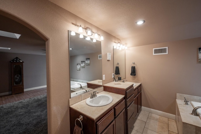 bathroom with a bath, vanity, a textured ceiling, and tile patterned floors