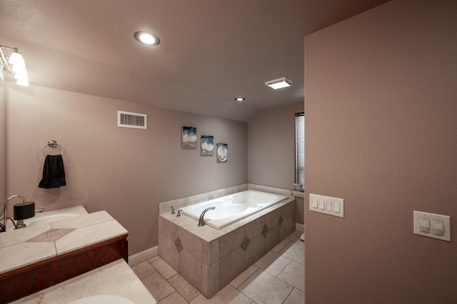 bathroom with tile patterned flooring, vanity, and tiled tub