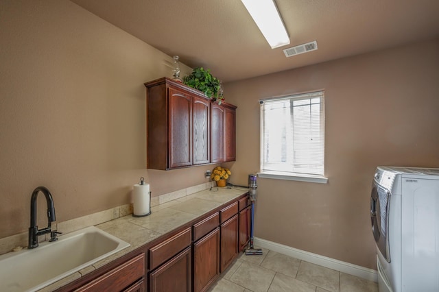 washroom with washer and dryer, light tile patterned flooring, cabinets, and sink