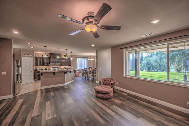 living area with ceiling fan with notable chandelier and dark hardwood / wood-style floors