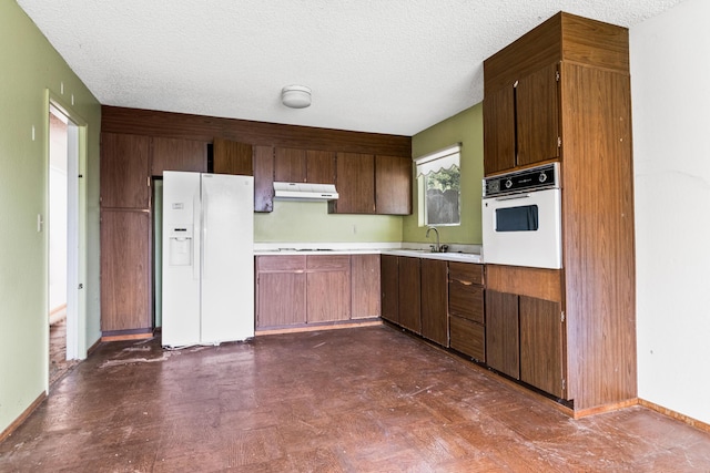 kitchen featuring sink, white appliances, and a textured ceiling