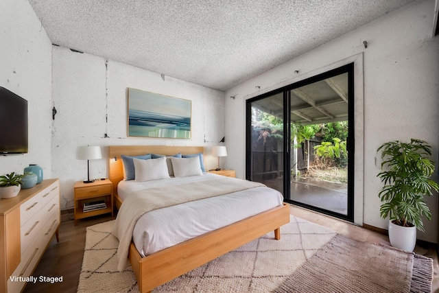 bedroom with a textured ceiling, access to outside, and hardwood / wood-style flooring