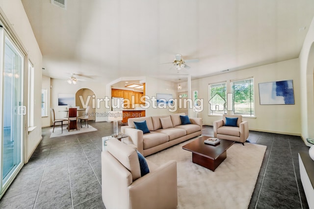 living room with ceiling fan and dark tile patterned floors