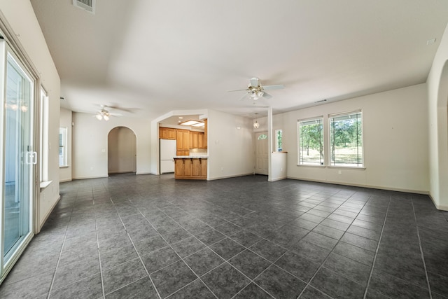 unfurnished living room with ceiling fan and dark tile patterned flooring