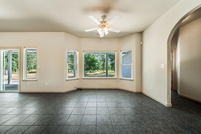 spare room with ceiling fan and dark tile patterned floors