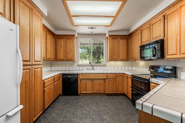 kitchen with sink, tile counters, and black appliances