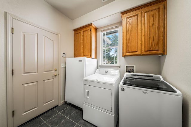 washroom featuring washing machine and clothes dryer, cabinets, and dark tile patterned flooring