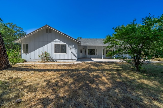 rear view of property with a patio and a lawn