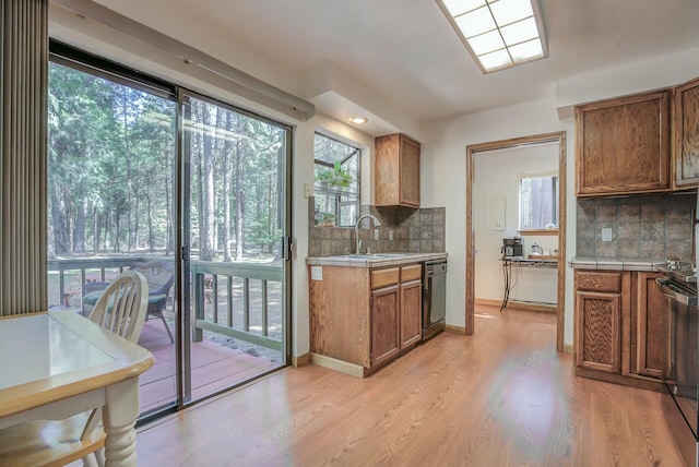 kitchen with dishwasher, light wood-type flooring, decorative backsplash, and sink