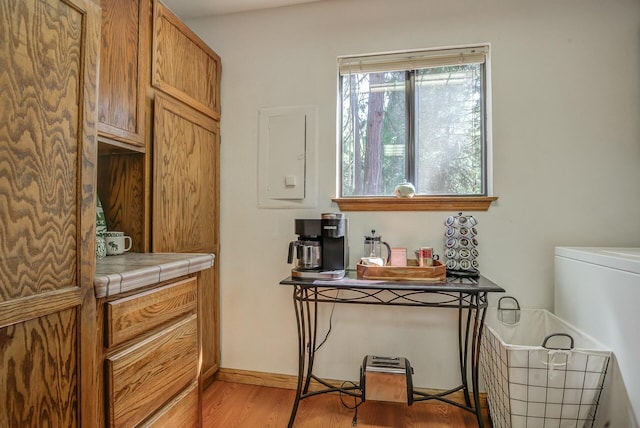 kitchen with tile counters, washer / dryer, and light hardwood / wood-style flooring