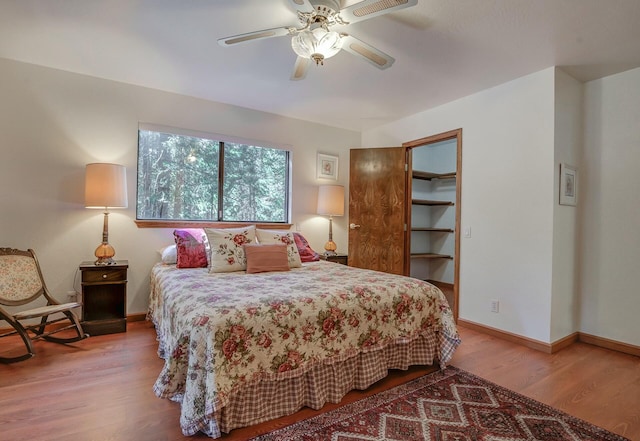 bedroom with a walk in closet, ceiling fan, a closet, and hardwood / wood-style flooring