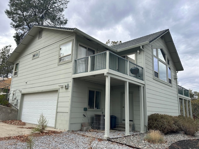 view of side of home featuring central air condition unit, a balcony, and a garage