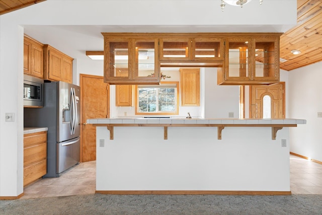 kitchen with tile countertops, a kitchen bar, lofted ceiling, and stainless steel appliances